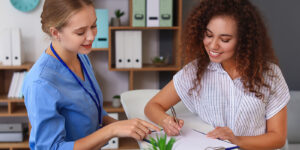 Smiling health worker sitting with patient happily completing paperwork